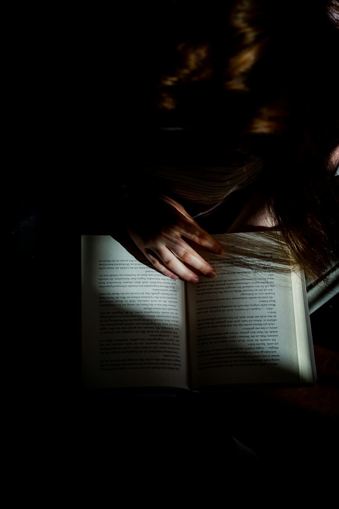 Person reading a book by a window with warm light