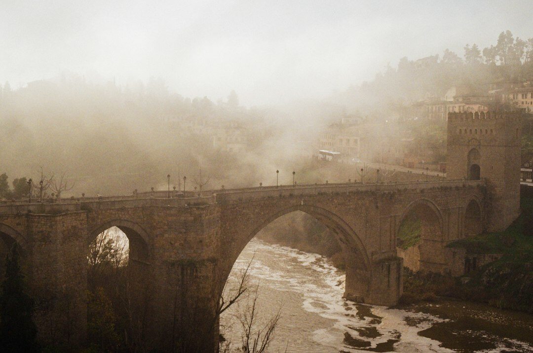 Old stone bridge over a river shrouded in mist