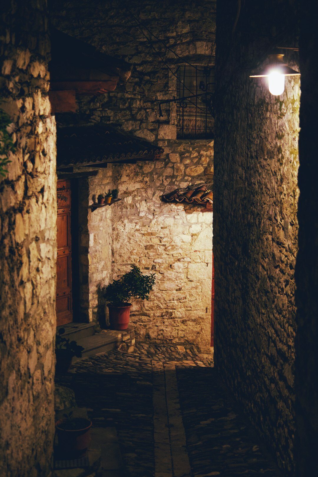 Narrow old stone alley with a single lamp at night
